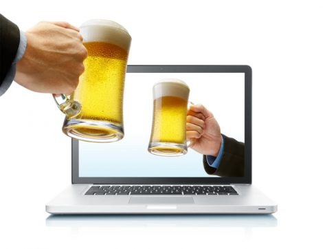 Manos brindando con cerveza desde el ordenador